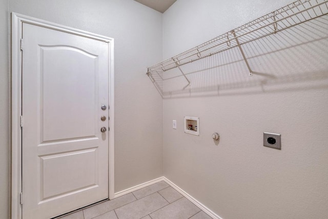 clothes washing area with light tile patterned flooring, hookup for a washing machine, hookup for an electric dryer, laundry area, and baseboards