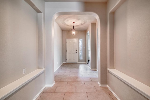 interior space featuring baseboards, arched walkways, and light tile patterned flooring