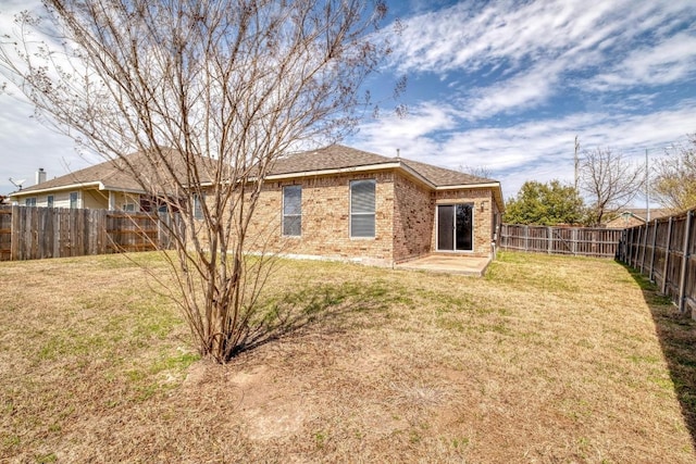 back of house featuring a fenced backyard, a lawn, and brick siding