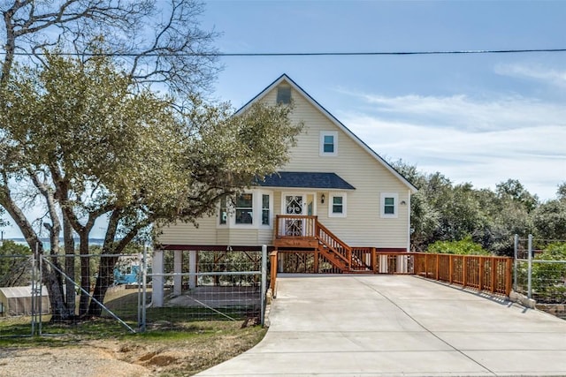 view of front of property with driveway, fence, and roof with shingles