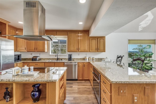 kitchen with a peninsula, a sink, appliances with stainless steel finishes, open shelves, and island exhaust hood