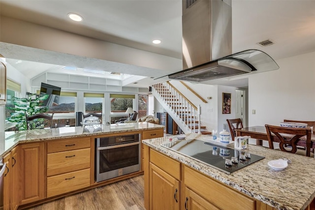 kitchen with island range hood, visible vents, black electric cooktop, light wood-style floors, and stainless steel oven