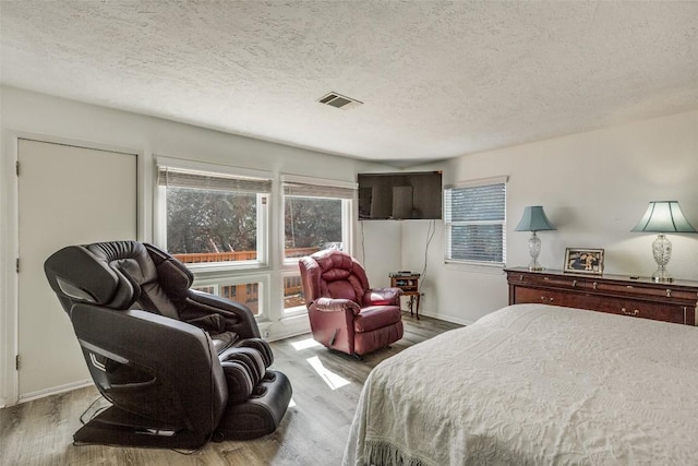 bedroom featuring a textured ceiling, visible vents, and wood finished floors