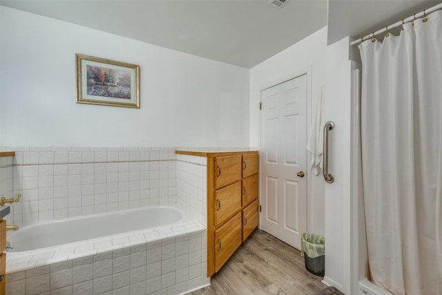 bathroom with a bath, curtained shower, and wood finished floors