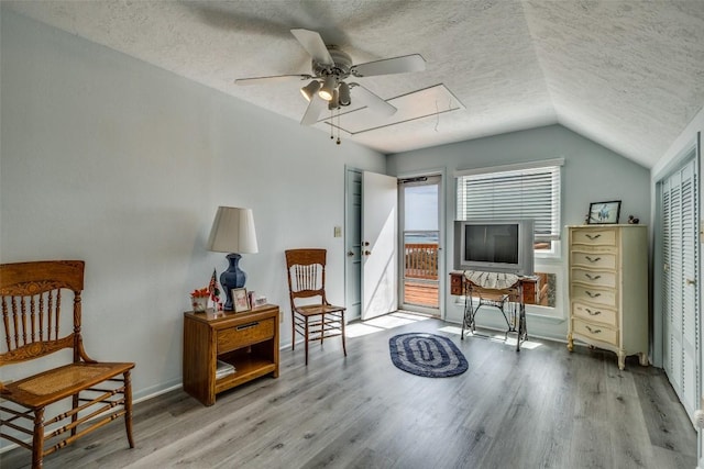 sitting room featuring lofted ceiling, attic access, a textured ceiling, and wood finished floors