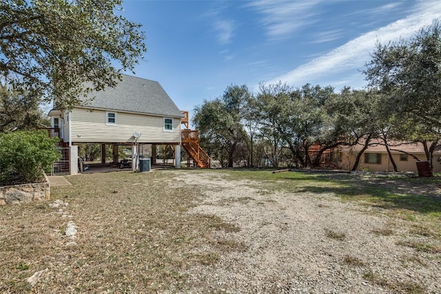 view of yard with a carport, stairway, and central air condition unit