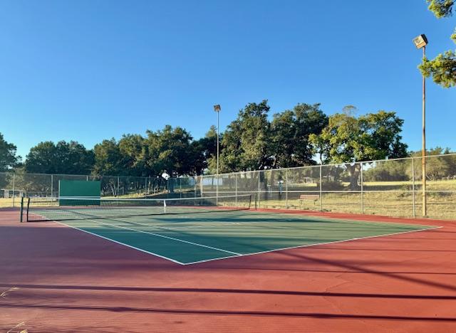 view of tennis court featuring community basketball court and fence