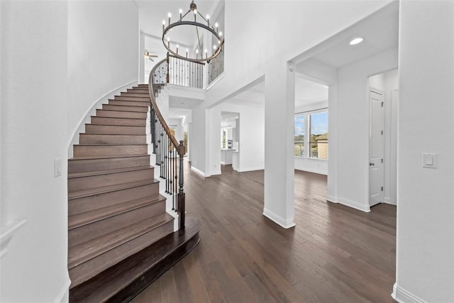 foyer with dark wood-style floors, stairway, a towering ceiling, and baseboards