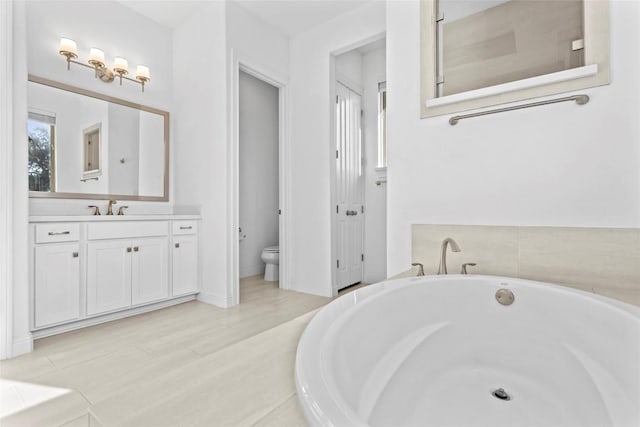 full bath featuring a garden tub, vanity, and toilet