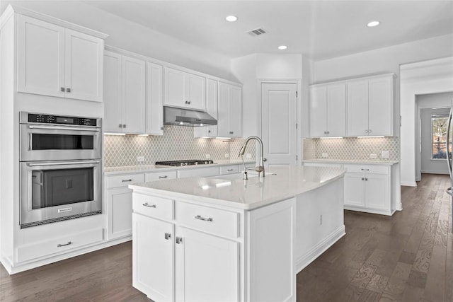 kitchen with dark wood-style floors, stainless steel appliances, light countertops, white cabinets, and under cabinet range hood