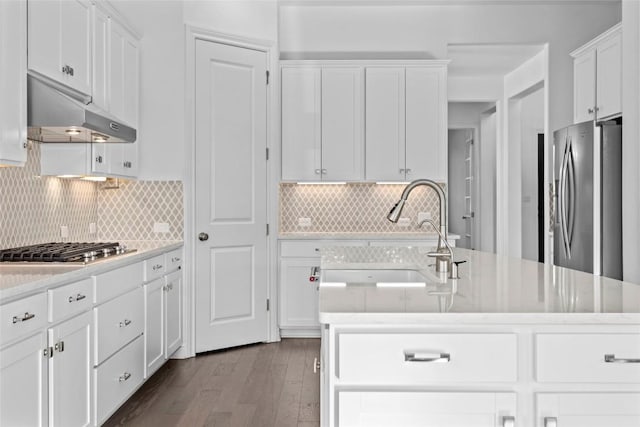 kitchen featuring appliances with stainless steel finishes, light countertops, a sink, and under cabinet range hood