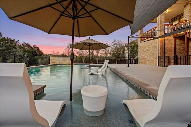 pool at dusk featuring a fenced in pool and fence