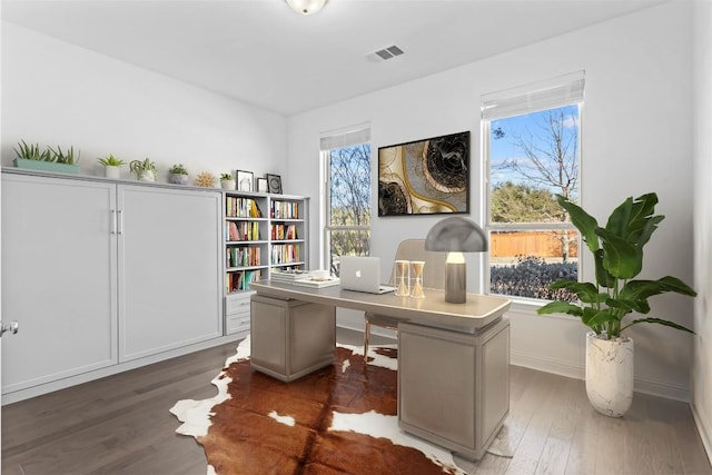 office area featuring dark wood-style floors, a healthy amount of sunlight, visible vents, and baseboards