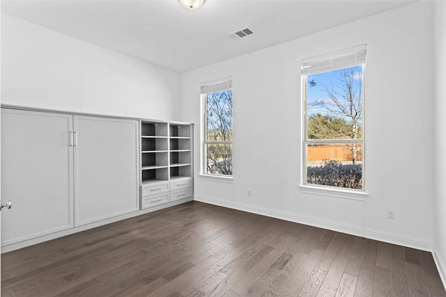 spare room with baseboards, visible vents, and dark wood finished floors