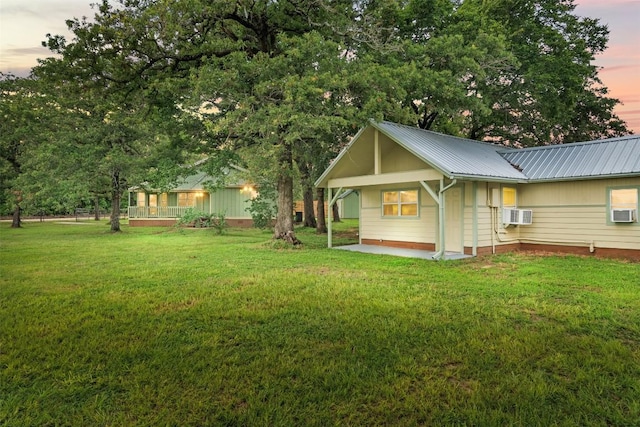 back of property at dusk with metal roof, a lawn, and an AC wall unit