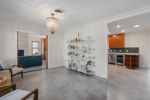 interior space featuring finished concrete flooring, visible vents, baseboards, a fireplace, and wine cooler