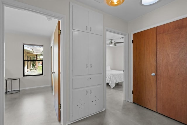 corridor with baseboards and finished concrete flooring