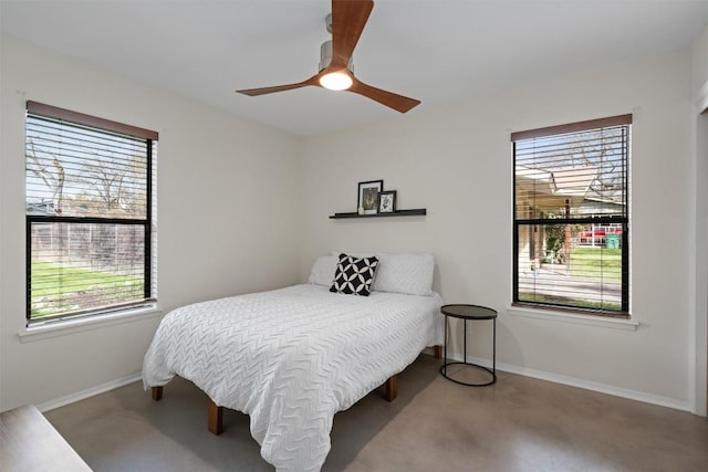 bedroom with baseboards, finished concrete flooring, and a ceiling fan