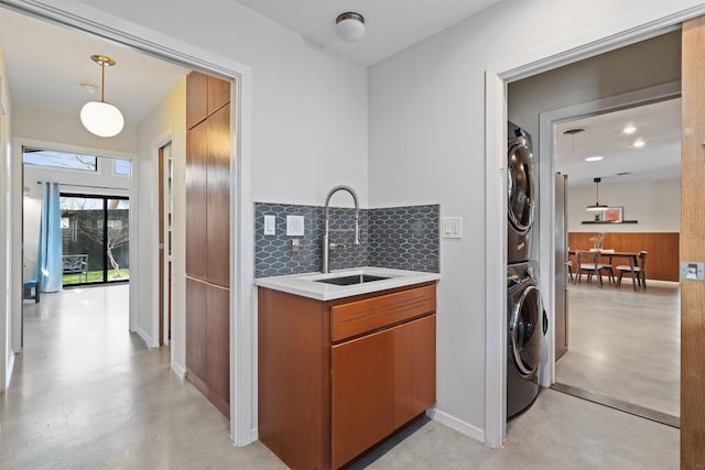 washroom featuring stacked washer / dryer, laundry area, and a sink