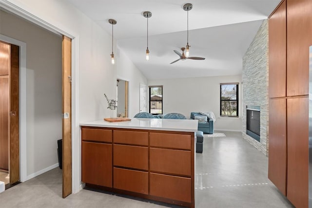 kitchen with concrete floors, a stone fireplace, vaulted ceiling, light countertops, and open floor plan