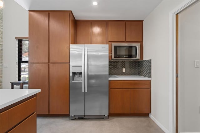 kitchen with stainless steel appliances, brown cabinets, backsplash, and light countertops