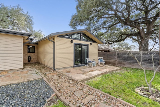 back of house with brick siding, a patio, and fence