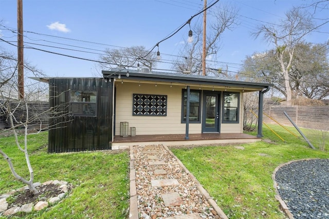 rear view of house with a lawn and fence