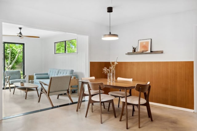 4810 Enchanted Ln, Austin, TX 78745 - dining space with healthy amount of natural light, wooden walls, wainscoting, finished concrete flooring, and ceiling fan