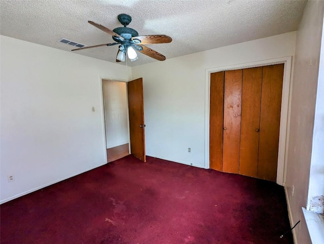 unfurnished bedroom featuring a closet, visible vents, carpet flooring, ceiling fan, and a textured ceiling