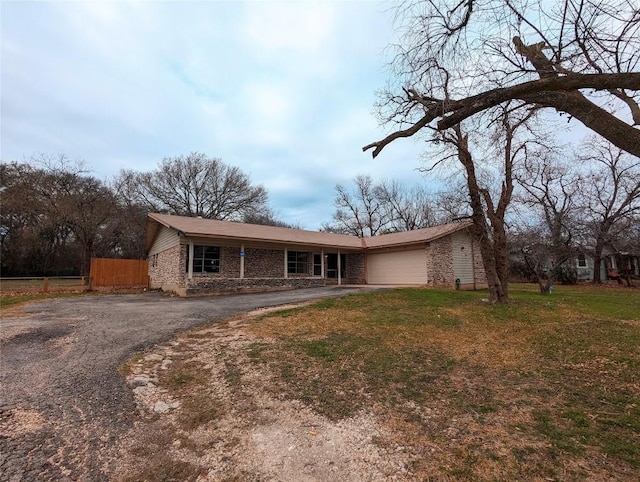 view of front of house featuring aphalt driveway, a garage, brick siding, fence, and a front lawn