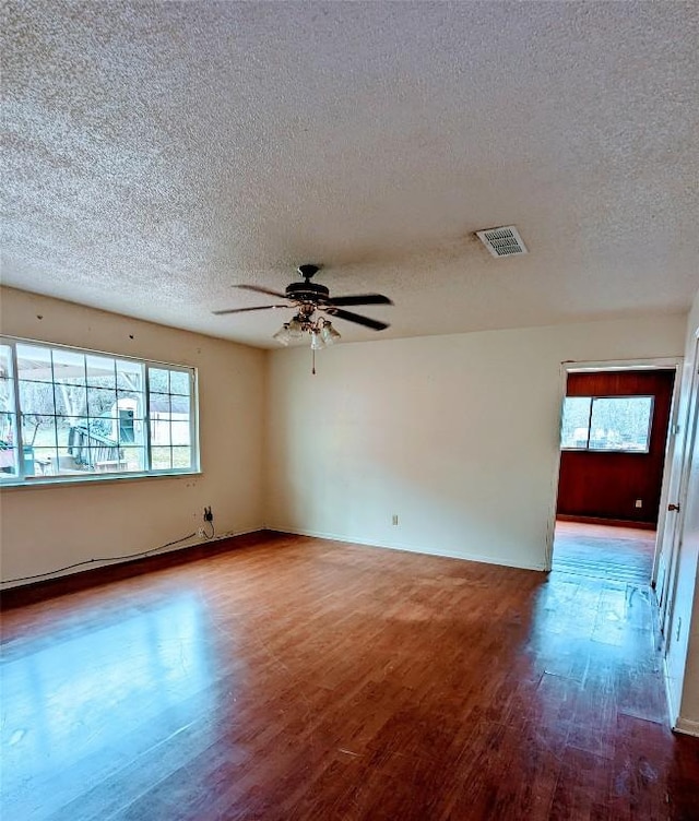 unfurnished room featuring visible vents, plenty of natural light, and wood finished floors