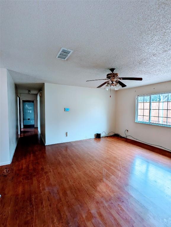 spare room with a ceiling fan, visible vents, a textured ceiling, and wood finished floors