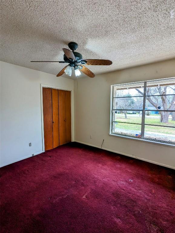 unfurnished bedroom with a textured ceiling, carpet floors, a closet, and baseboards