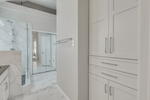 bathroom with marble finish floor, baseboards, vanity, and a marble finish shower