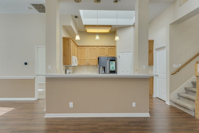 kitchen with dark wood-style floors, visible vents, a high ceiling, white microwave, and stainless steel fridge with ice dispenser