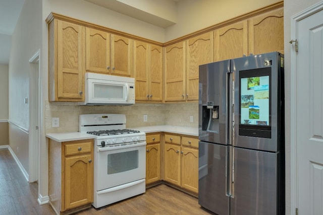 kitchen with white appliances, light wood finished floors, baseboards, light countertops, and backsplash