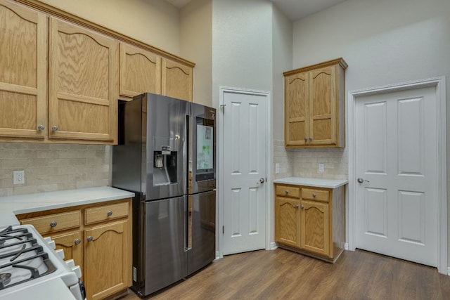 kitchen with white gas stove, tasteful backsplash, light countertops, dark wood-type flooring, and stainless steel fridge