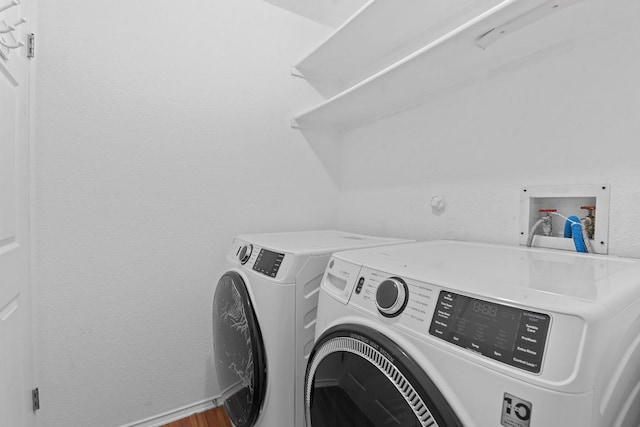 laundry room with baseboards, wood finished floors, laundry area, and washing machine and clothes dryer