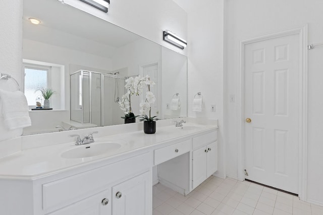 full bathroom featuring tile patterned flooring, double vanity, a stall shower, and a sink