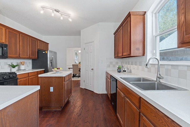 kitchen featuring black appliances, a sink, dark wood finished floors, light countertops, and decorative backsplash