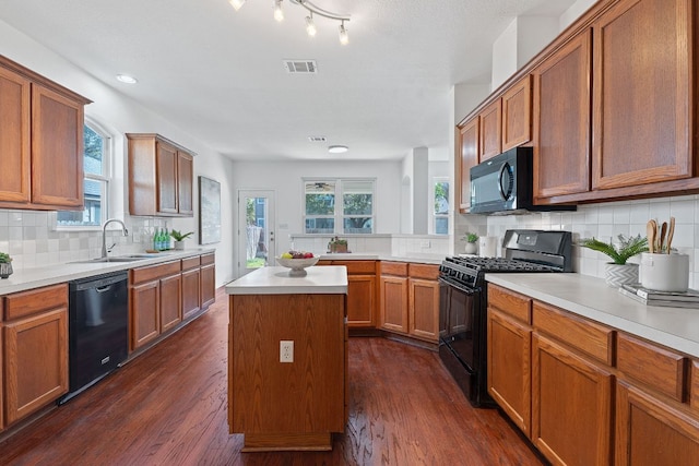 kitchen featuring a sink, visible vents, black appliances, and dark wood finished floors