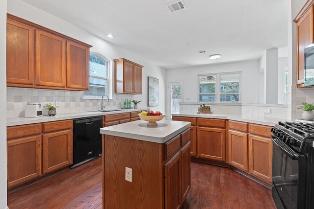 kitchen with a sink, visible vents, black appliances, and dark wood-style floors