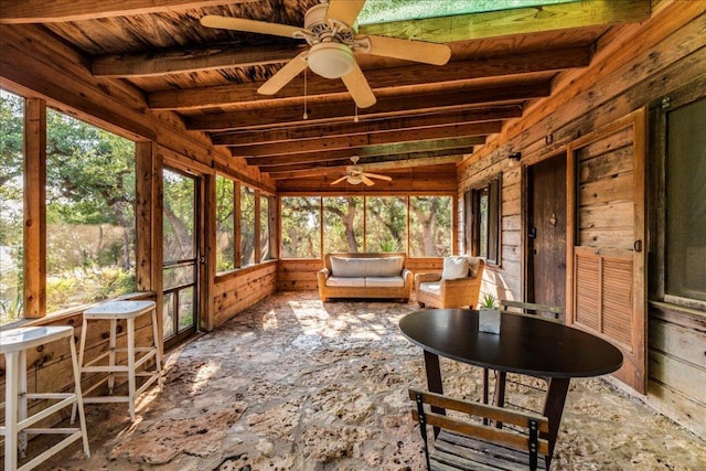 unfurnished sunroom featuring wooden ceiling, a healthy amount of sunlight, beamed ceiling, and ceiling fan