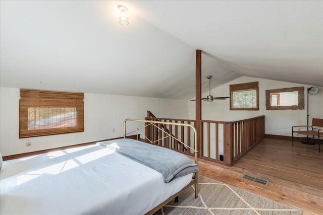 bedroom with lofted ceiling, visible vents, baseboards, and wood finished floors