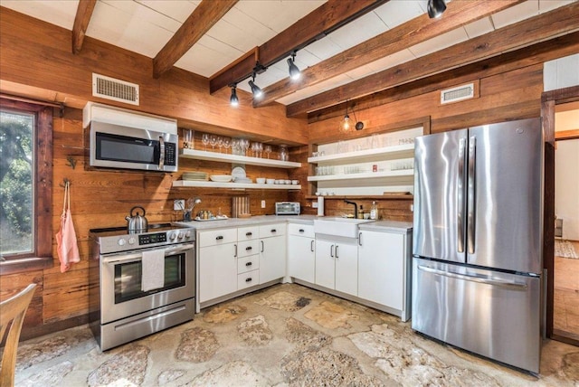 kitchen featuring stainless steel appliances, wood walls, a sink, visible vents, and open shelves