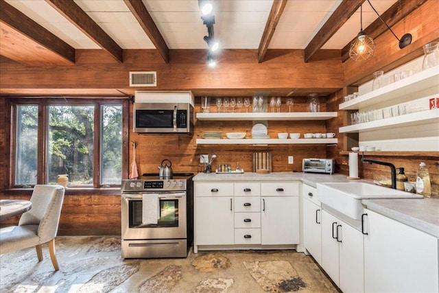 kitchen with open shelves, appliances with stainless steel finishes, visible vents, and wooden walls