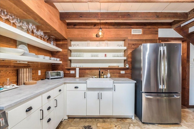 kitchen with freestanding refrigerator, a sink, wood walls, and open shelves