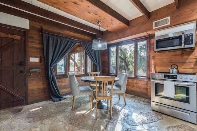 dining space featuring a wealth of natural light, beam ceiling, wood walls, and visible vents