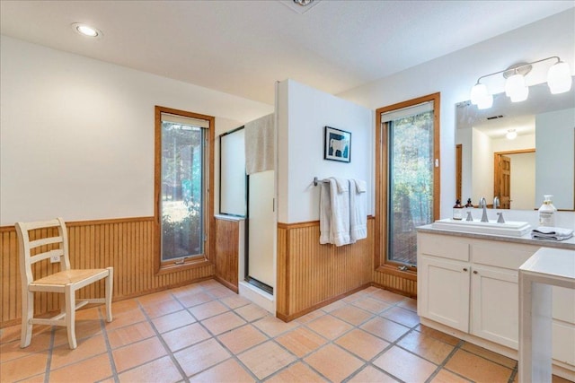 bathroom with a stall shower, wainscoting, wood walls, and vanity