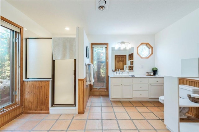 bathroom featuring wooden walls, a wainscoted wall, vanity, a shower stall, and tile patterned floors